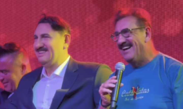 O apresentador Ratinho ao lado de sua estátua de cera recém-inaugurada no Dreamland Museu de Cera, em Foz do Iguaçu, acenando e sorrindo para o público.