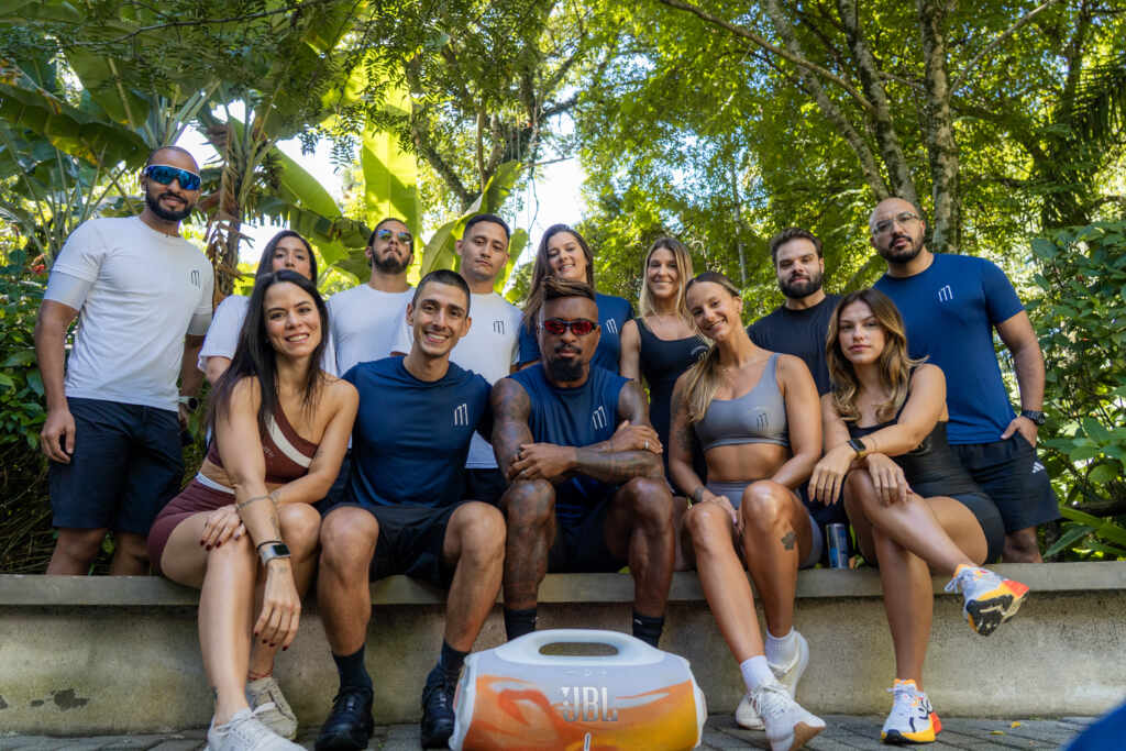 Zé Roberto e grupo posam após treino no Parque Ibirapuera durante o Programa Movimento 11; participantes usam roupas do evento e há uma caixa de som JBL no primeiro plano.
